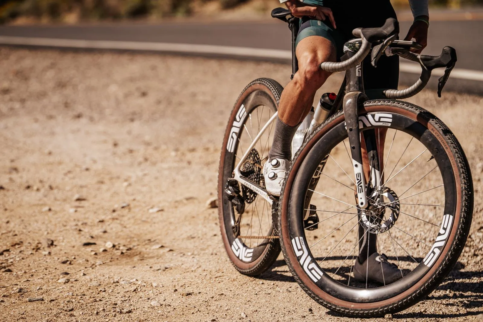 Close-up of ENVE carbon wheels and tan-wall tires on a dusty gravel track